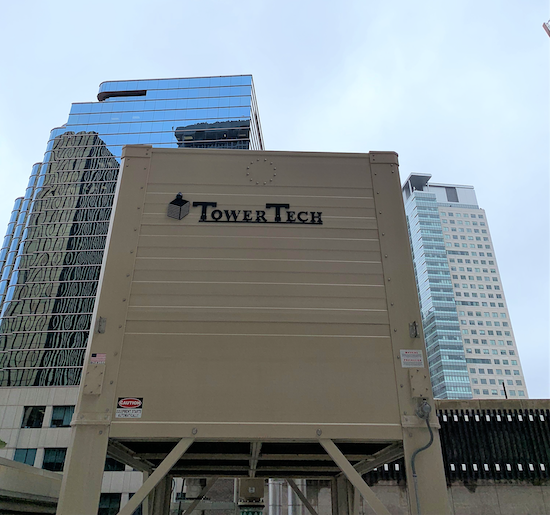 A TowerTech cooling tower unit installed on a rooftop, with city skyscrapers in the background.