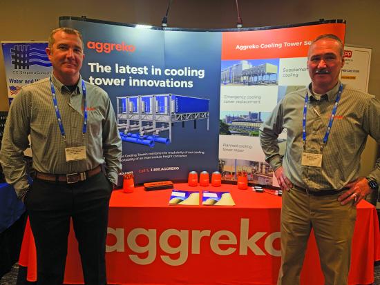 Two men stand at an Aggreko trade show booth with signage reading ‘The latest in cooling tower innovations.’