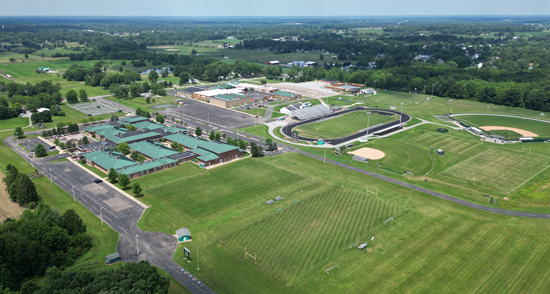 Aerial view of a school campus with buildings, a running track, and multiple athletic fields.